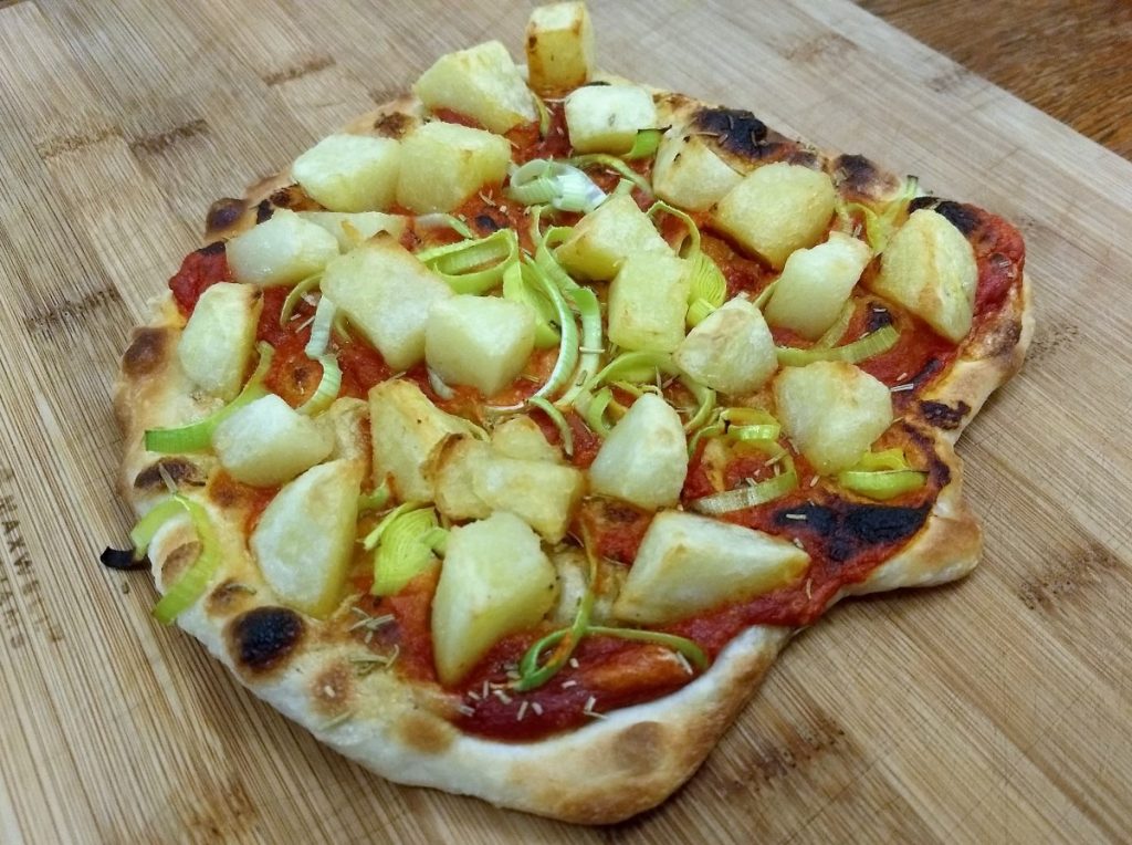 Pizza with roast potatoes and leeks on a chopping board